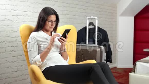 女商务人士用智能手机聊天在中档公寓放松视频的预览图