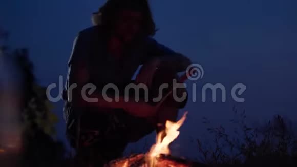 年轻的嬉皮士在海边玩篝火生火做香肠在舒适的夏天晚上聊天视频的预览图