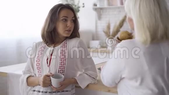 一个年轻迷人的女人喝茶或咖啡和她母亲说话的肖像把她的秘密和视频的预览图