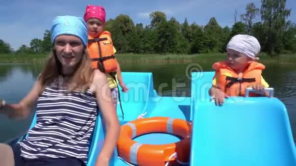 儿子女儿和母亲穿着救生衣漂浮在双体船上万向节运动视频的预览图