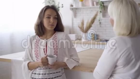一个年轻女人喝茶或咖啡和她母亲说话的肖像她和妈妈分享她的秘密视频的预览图