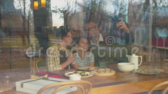 女儿和父母在咖啡馆打电话拍照视频的预览图