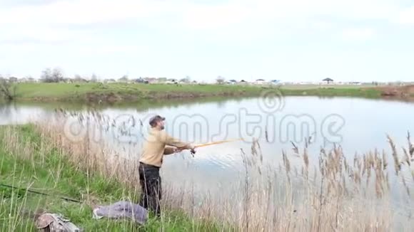 渔夫手里拿着鱼竿站在岸边的湖上秋日视频的预览图