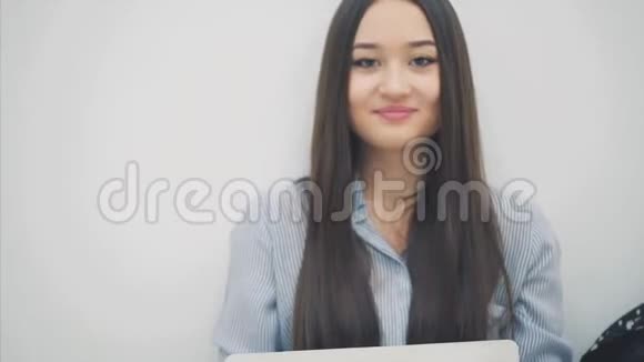 可爱的亚洲女孩长发膝盖上坐着笔记本电脑看着相机竖起大拇指视频的预览图