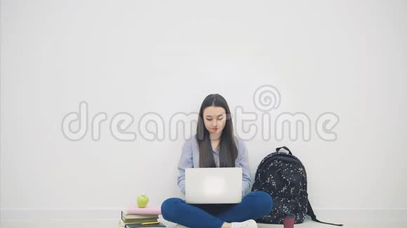 可爱的微笑亚洲学生坐在地板上的洛托斯位置笔记本电脑指着她的手指微笑视频的预览图