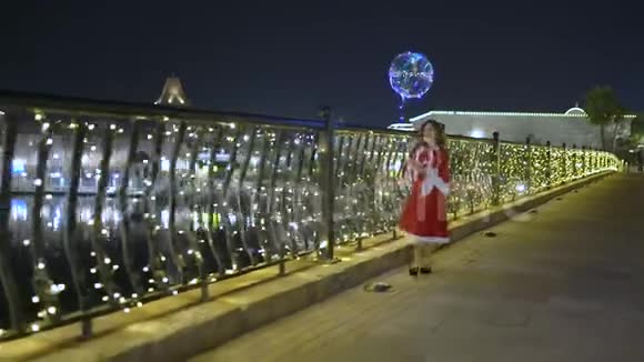 快乐的孩子在夜晚的城市散步圣诞节的光照穿着圣诞礼服的小女孩走着视频的预览图
