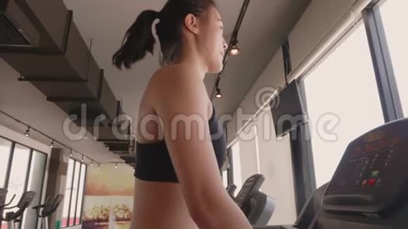 在健身运动健身馆里穿着运动服在跑步机上行走和慢跑的迷人亚洲女孩视频的预览图