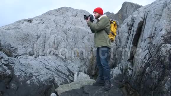 专业的自然摄影师带着相机在山顶环顾四周拍照视频的预览图