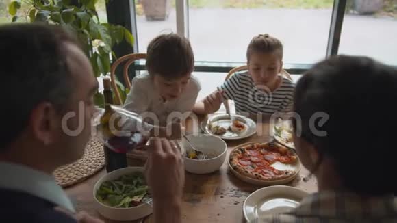 男孩把叉子放在盘子里女孩吃披萨父亲在咖啡馆里喝酒视频的预览图