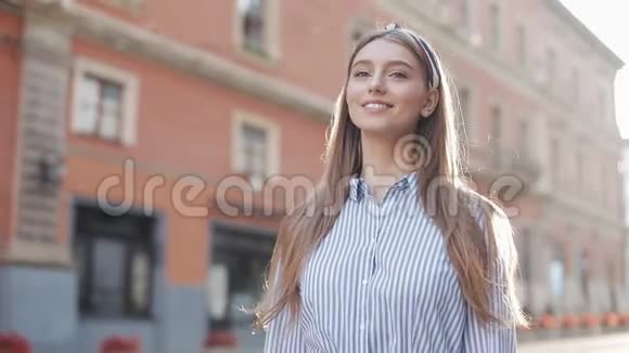 可爱的女人穿着蓝色和白色条纹连衣裙衬衫走在街上看着镜头旋转幸福的微笑视频的预览图