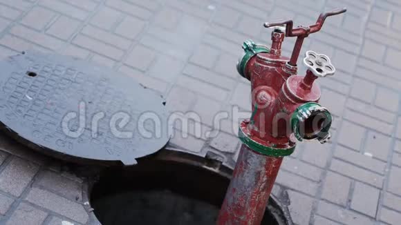 与城市中的一个开放舱口相连的特写消防栓旧红火栓视频的预览图