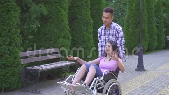 年轻积极的亚洲女性残疾人坐轮椅高兴地举起双手她和她的亚洲朋友慢莫玩得很开心视频的预览图