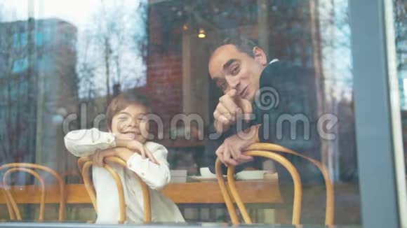 快乐的父子在咖啡馆里透过窗户视频的预览图