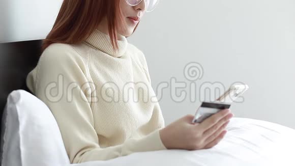 美女特写穿黄色毛衣用智能手机网上购物银行用信用卡在家生活视频的预览图