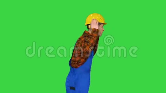 年轻的建筑工人戴着安全帽在绿色屏幕上跳嘻哈舞Chroma键视频的预览图