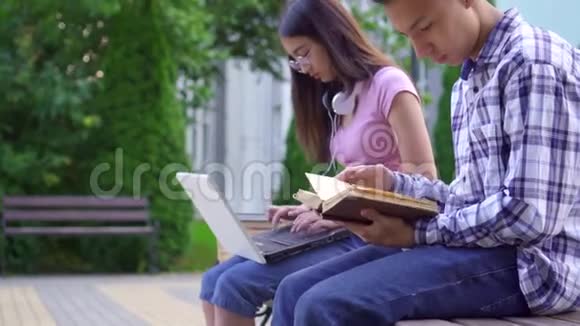 带书的年轻亚裔男学生和带笔记本电脑的年轻亚裔女性视频的预览图