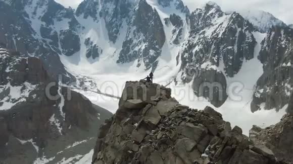 岩石峰上的两个登山者雪山鸟瞰图视频的预览图