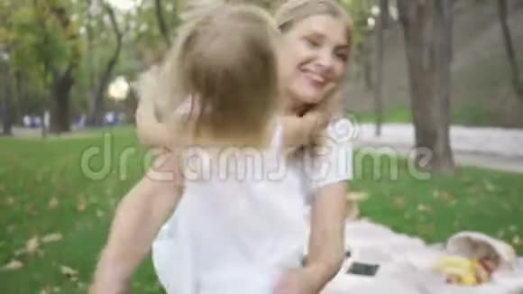 从后面看着小金发女孩朝她妈妈跑去漂亮的年轻女人拥抱她的女儿微笑着视频的预览图