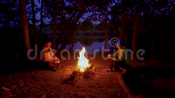 一男一女靠近夜林的火堆视频的预览图