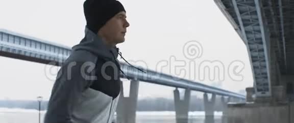 年轻运动员训练在寒冷的天气下在恶劣的环境下在城市空间中奔跑视频的预览图