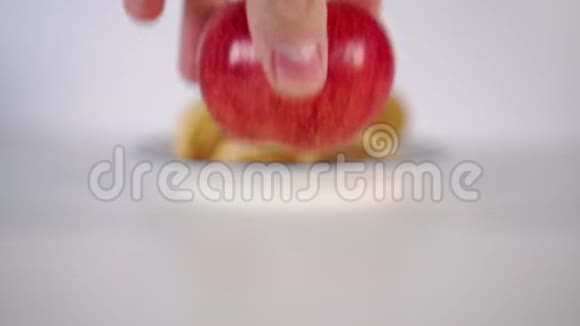 手在一张白色桌子上的盘子里的薯片前摘一个成熟的红苹果视频的预览图