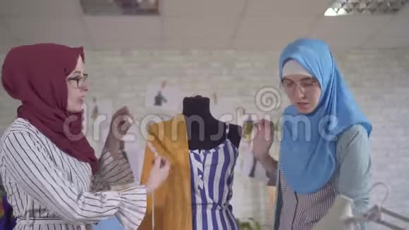 年轻的穆斯林女性时装设计师在国家头巾在一个现代工作室关闭视频的预览图