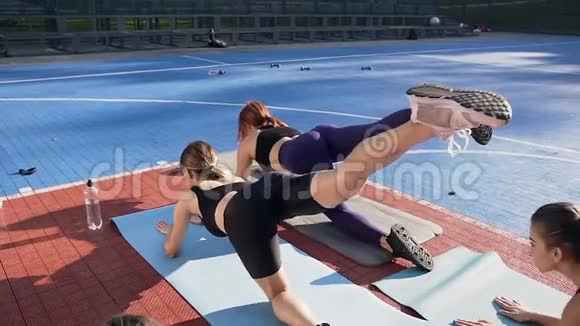 运动服中肌肉发达的年轻女性在户外瑜伽垫上用一条腿做伸展运动视频的预览图