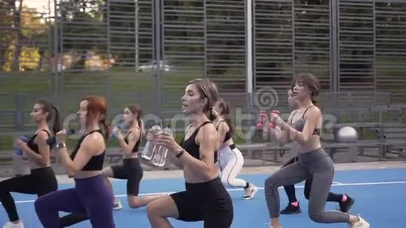年轻漂亮的健身妇女用哑铃做训练运动以加强户外身体的肌肉视频的预览图