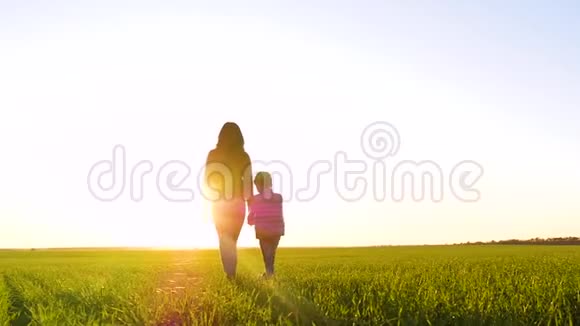 一个女人和一个孩子在夕阳下牵手的剪影视频的预览图