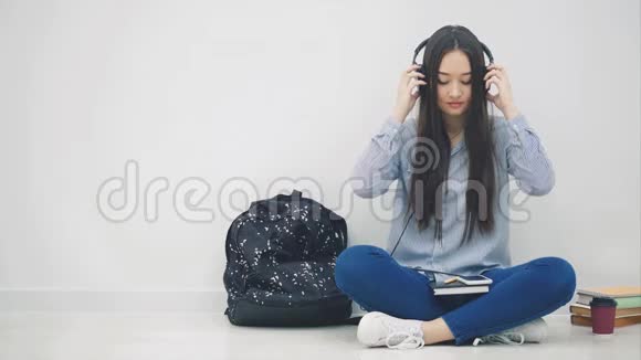 启发年轻的亚洲女孩戴着耳机听着音乐坐在莲花的位置视频的预览图