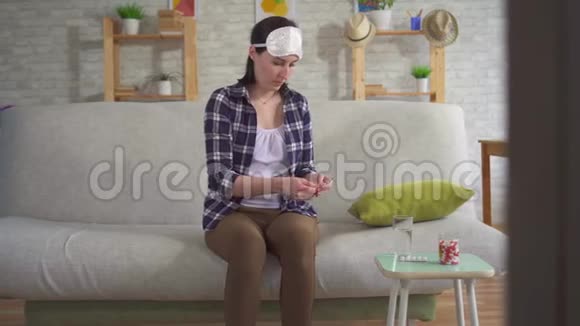 年轻女人吃安眠药戴着面具睡在沙发上睡觉视频的预览图