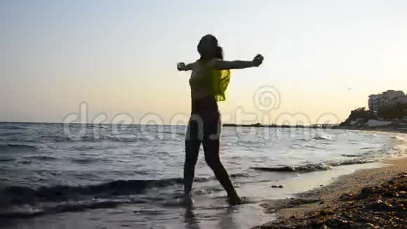 在日落时分美丽的少女在沙滩上精神焕发视频的预览图