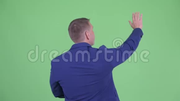 成熟的男性商人挥舞着手的后视图视频的预览图