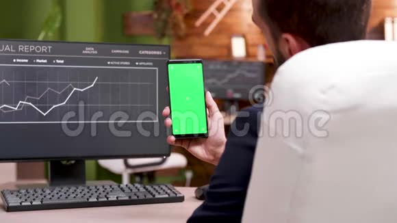 现代工作场所的商人拿着绿色屏幕的电话视频的预览图