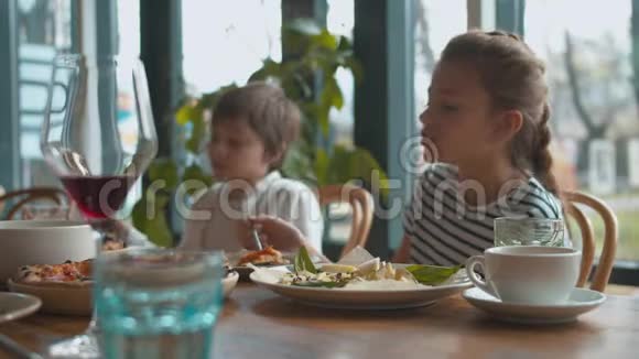 妈妈和儿子从盘子里拿奶酪女孩吃披萨视频的预览图
