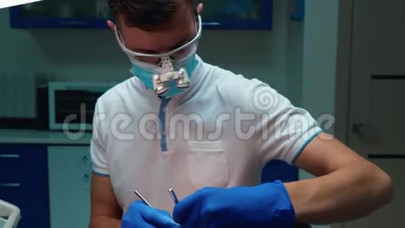 戴眼镜戴口罩戴牙镜戴牙镜牙齿的年轻英俊牙医视频的预览图