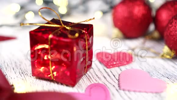 红色礼盒搭配金结和粉心特写明亮的装饰球和丝带圣诞树亮灯亮灯视频的预览图