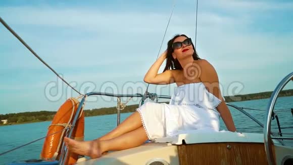 穿着白色礼服坐着帆船享受暑假的积极女性视频的预览图