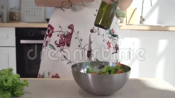 女人的手把橄榄油倒入玻璃碗里配上新鲜的春天沙拉把做饭的女人的手收起来健康生活方式视频的预览图