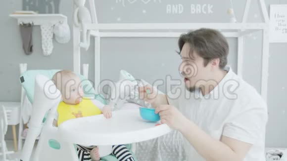 父亲在家里坐在高椅子上喂婴儿视频的预览图
