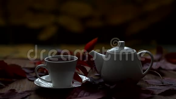 桌子上是热茶和茶壶蒸汽来自一个杯子一滴茶从茶壶嘴里流下来秋季热饮视频的预览图