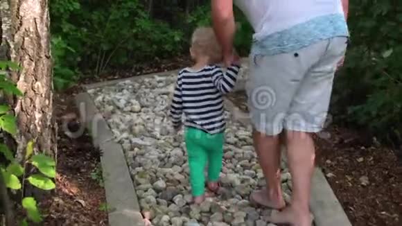 爸爸带着小儿子走过健康的足部赤脚按摩视频的预览图