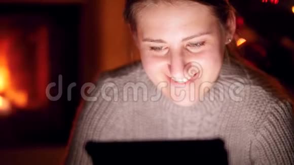 4k特写视频微笑的年轻女子坐在黑暗的客厅里看着数码平板电脑屏幕视频的预览图