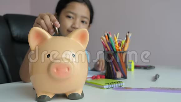 特写小亚洲女孩把硬币放进储蓄罐比喻为更好的未来省钱选重点浅深度的视频的预览图