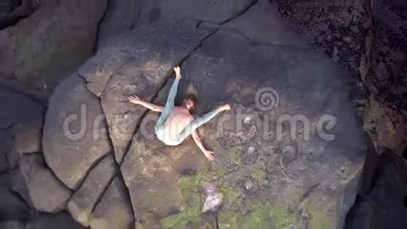 苗条的女人在石头上练习现代拉伸姿势视频的预览图
