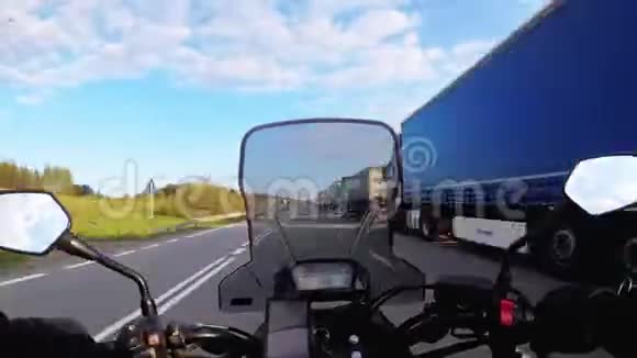 摩托车在道路上沿着停着的卡车柱行驶视频的预览图