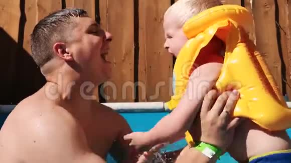 父子俩沉迷泳池在孩子身上是一件黄色的游泳背心可以在游泳池里安全游泳快乐c的概念视频的预览图