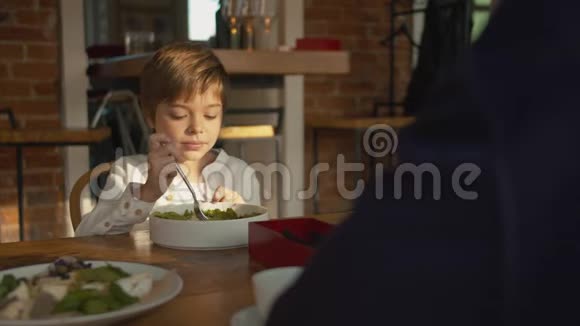 父子在午餐时男孩用叉子搅拌沙拉视频的预览图