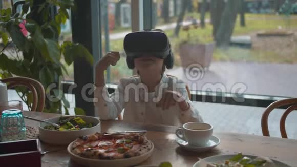 午餐时看着虚拟现实眼镜的男孩视频的预览图