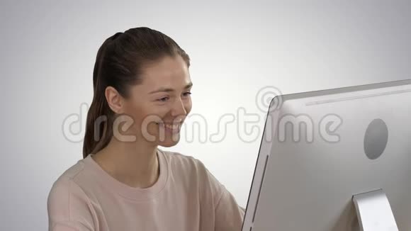 学生金发女孩看着电脑显示器在渐背景上微笑视频的预览图